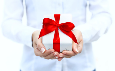 Woman's hand with a small white gift box with bow isolated on white background