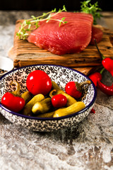 Tuna steak on a wooden board with pepper and cucumber