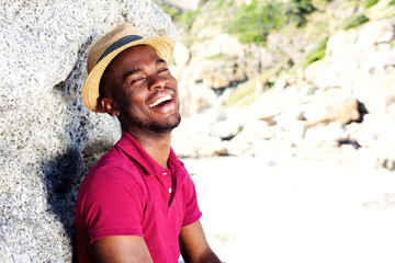 Wall Mural - Happy young guy in hat smiling at the beach