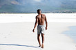 © mimagephotos - Young man walking barefoot on beach