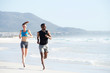 © mimagephotos - Fit young man and woman running along the beach
