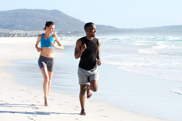 Wall Mural - Healthy active couple running by water on the beach