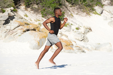 Wall Mural - Healthy active young african man running on the beach