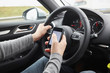 © Connect Images - Cropped shot of man using smartphone whilst driving