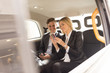 © Connect Images - Businessman and businesswoman using smartphone in black cab, London, UK