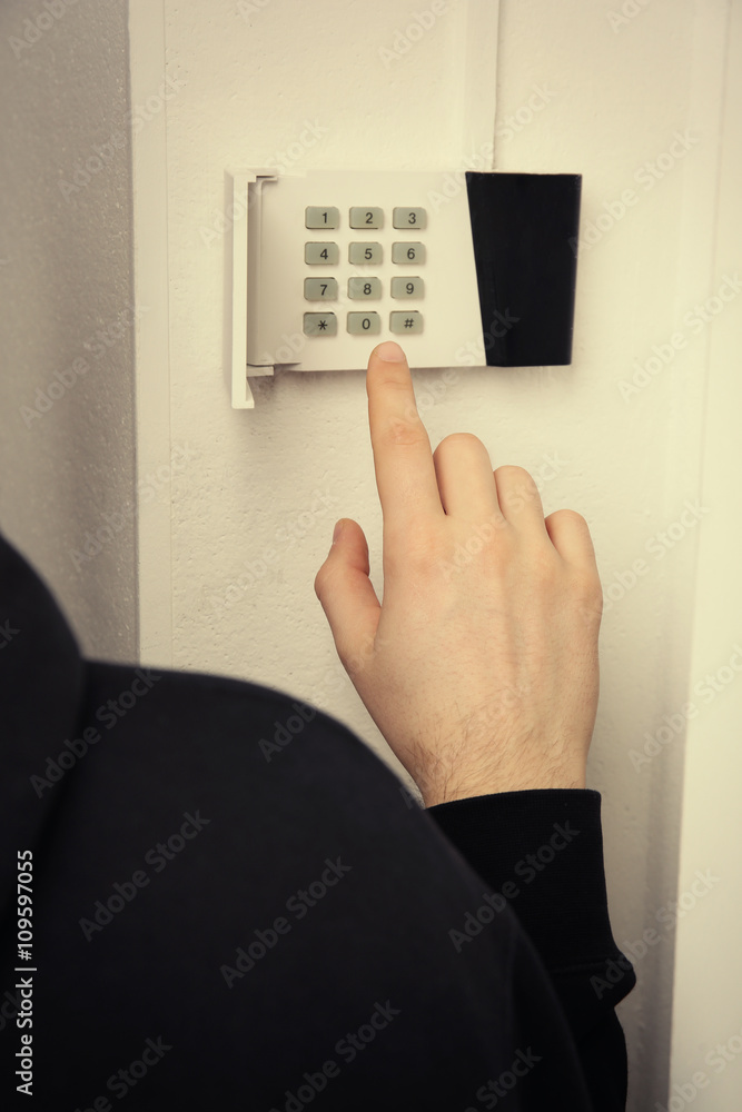 Security alarm keypad with male hand, closeup