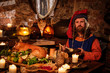 © Nejron Photo - Medieval man eat and drink in ancient castle kitchen interior.