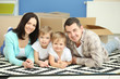 © Africa Studio - Moving concept. Happy family lying on carpet with cardboard boxes in new house