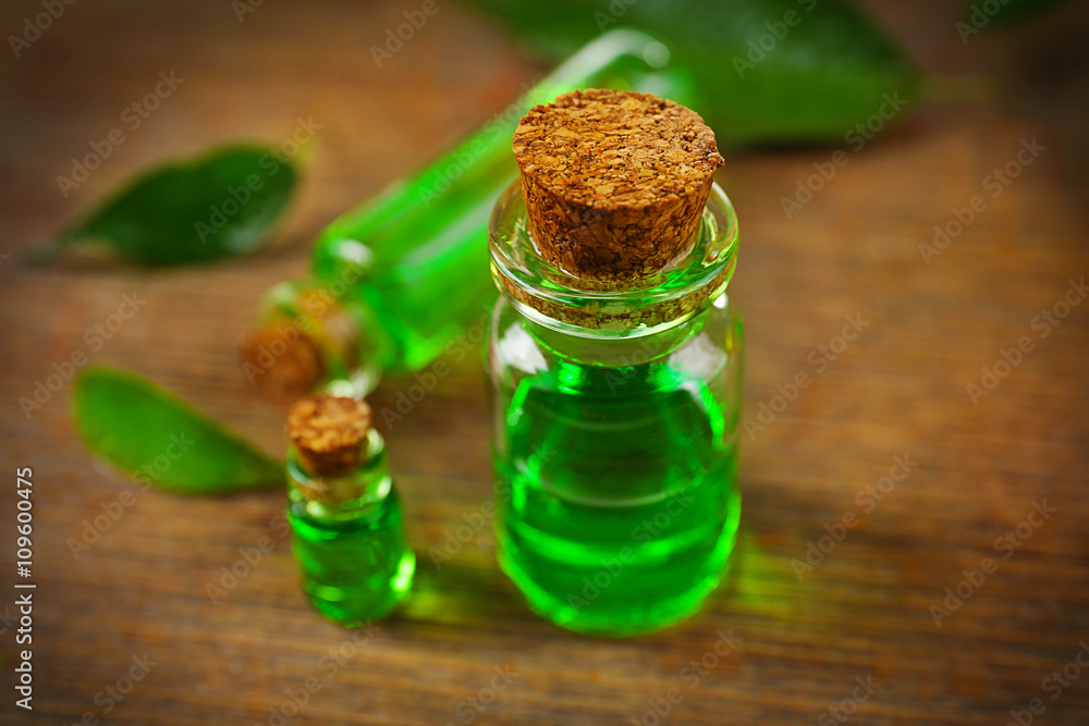 Bottles of tea oil on wooden background