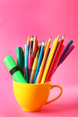 Wall Mural - Colorful stationery in yellow cup on pink background