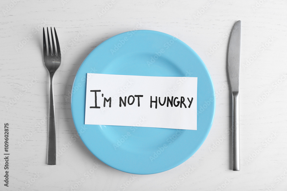 Words I'm not hungry in a plate on white table. Top view.