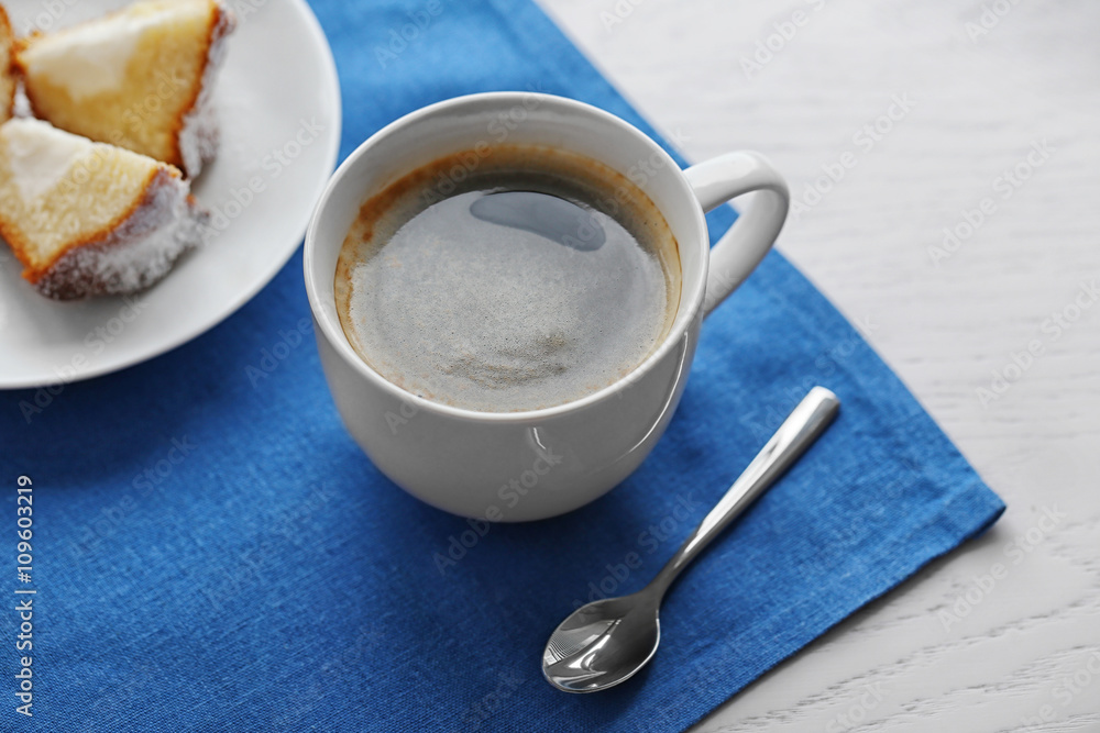 Cup of coffee with cake on a blue napkin