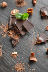 Sticker - Pieces of chocolate with hazelnuts and fresh mint on black wooden background