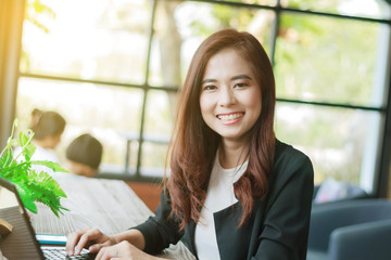 Asian business women using notebook and business women smiling h