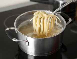 Spaghetti in spoon over pan closeup