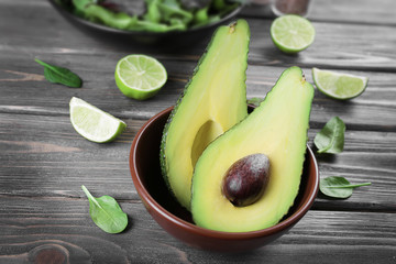 Fototapete - Fresh avocado in bowl on wooden table