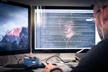 Hacker or software program developer reflection in the monitor w