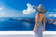 Luxury travel vacation woman looking at view on Santorini famous Europe travel destination. Elegant young lady living fancy jetset lifestyle wearing dress on holidays. Amazing view of sea and Caldera.