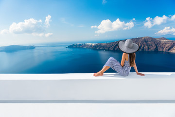 Fototapete - Europe Greece Santorini travel vacation. Woman looking at view on famous travel destination. Elegant young lady living fancy jetset lifestyle wearing dress on holidays. Amazing view of sea and Caldera