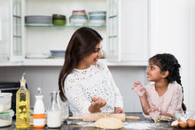 Indian Mother And Daughter Playing While Cooking