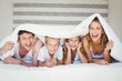 © WavebreakmediaMicro - Portrait of family covered with duvet on bed