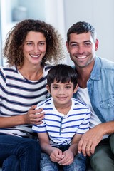 Wall Mural - Portrait of happy family sitting together on sofa