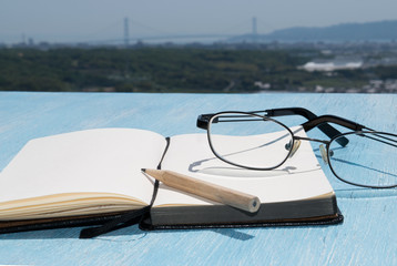 Glasses with nitepad on the wooden blue table