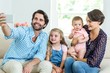 © WavebreakmediaMicro - Family taking selfie while sitting on sofa