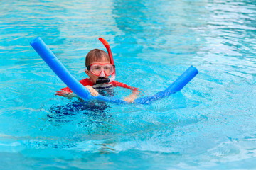 Little boy learns swimming alone with pool noodle