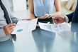 © DragonImages - Close-up image of business people analyzing charts and graphs