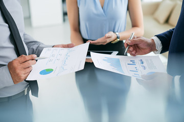 Close-up image of business people analyzing charts and graphs