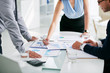 © DragonImages - Cropped image of business people discussing papers on table