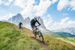 © RooM The Agency - A man and a woman on  mountain bikes racing along trail in the Dolomites,  Val Gardena, Italy