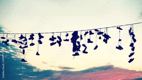 Tapeta ścienna Retro stylizowane sylwetki buty wiszące na kabel o zachodzie słońca, koncepcja buntu nastolatków.