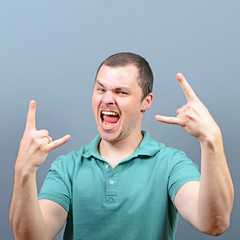 Wall Mural - Portrait of a man showing rock gesture against gray background