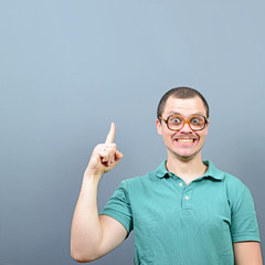 Wall Mural - Portrait of funny nerd guy having an idea  and showing at empty