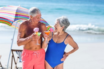 Wall Mural - Cute mature couple having cocktails on the beach