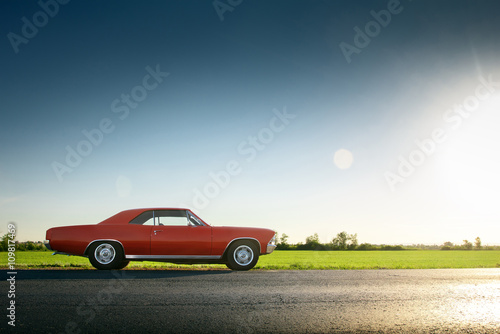 Retro red car standing on asphalt road at sunset © Ivan Kurmyshov