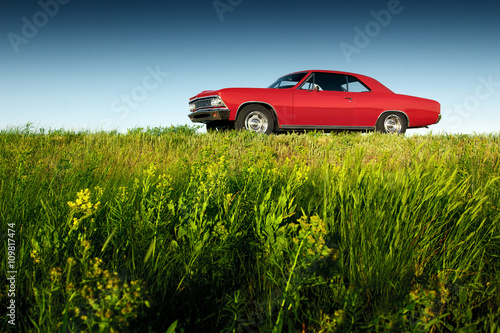 Retro red car standing on asphalt road at sunset Poster