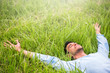 © iuricazac - Happy beautiful man lying on the green grass with arms outstretched