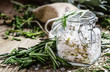 Sea salt with dried rosemary in a glass jar, vintage wooden back