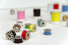 Metal Bobbin Spools With Colorful Thread Arranged In White Background