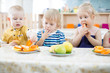 © Andrey Kuzmin - Tree funny kids eating fruits in day care centre