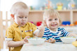 © Andrey Kuzmin - Two funny smiling little kids eating in kindergarten