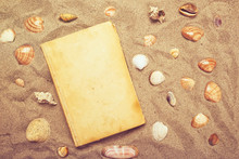 Vintage Book And Sea Shells On Sandy Beach