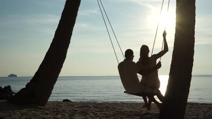 Poster - Young couple on a swing at the tropical beach against the sea
