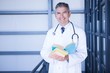 © WavebreakMediaMicro - Portrait of male doctor standing with medical book