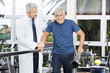 Doctor Motivating Senior Man To Walk In Fitness Studio