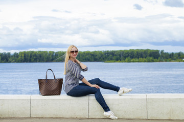 Young beautiful woman in blue jeans sitting in summer street par