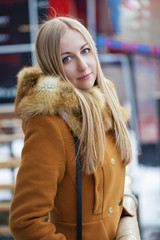 Happy young blonde woman on the background of a winter street